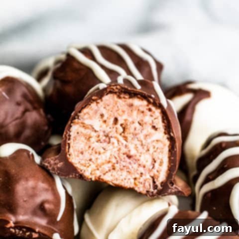 Elegant white chocolate raspberry truffles, featuring a creamy raspberry center enrobed in white chocolate and dusted with cocoa powder, a perfect Valentine's Day confection.