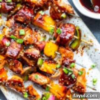 Grilled Teriyaki Chicken Skewers 3 Overhead shot of perfectly arranged grilled chicken teriyaki kabobs on a white plate, set against a blue counter.