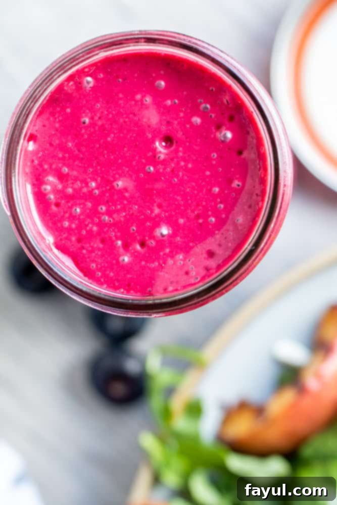 Overhead shot of blueberry dressing in a mason jar on a white counter, ready for use.