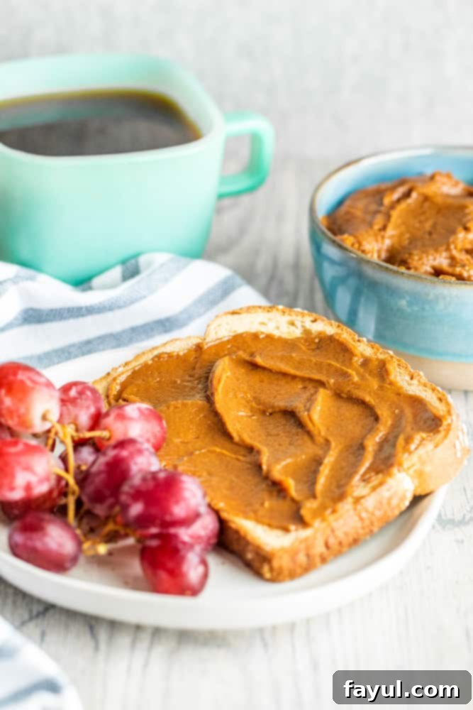 The 5-Minute Cookie Butter Hack 5 Golden cookie butter spread on a piece of toasted bread, resting on a white counter with a cup of coffee in the blurred background.