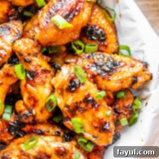 Deliciously glazed BBQ Peach Grilled Chicken Wings in a white bowl on a white counter, ready to be served with dipping sauce.