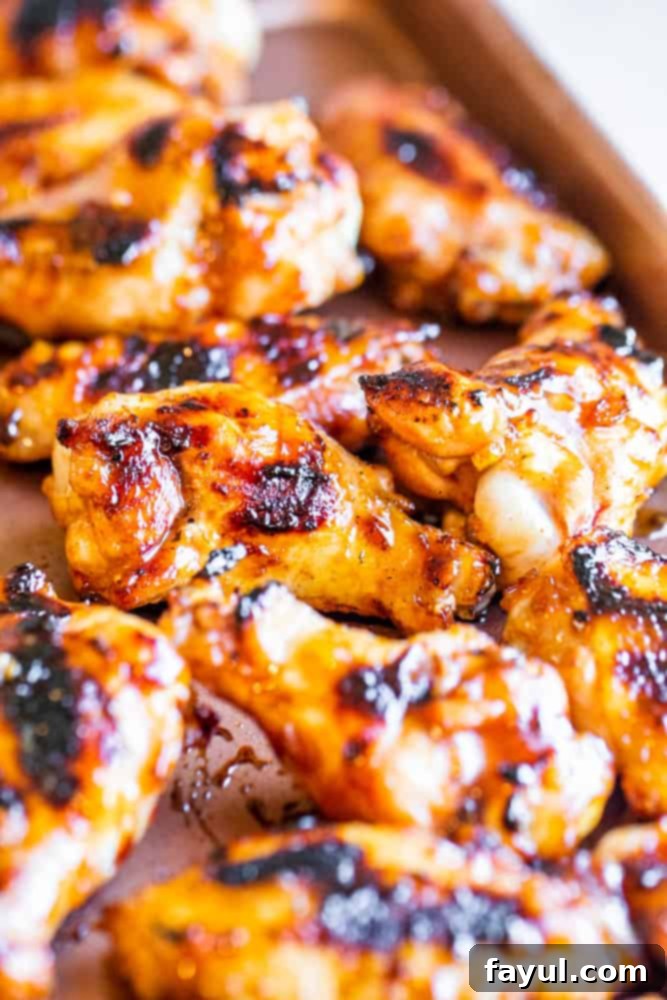 Close-up of perfectly cooked BBQ Peach Chicken Wings on a copper cookie sheet, showcasing their rich color and delicious char marks.
