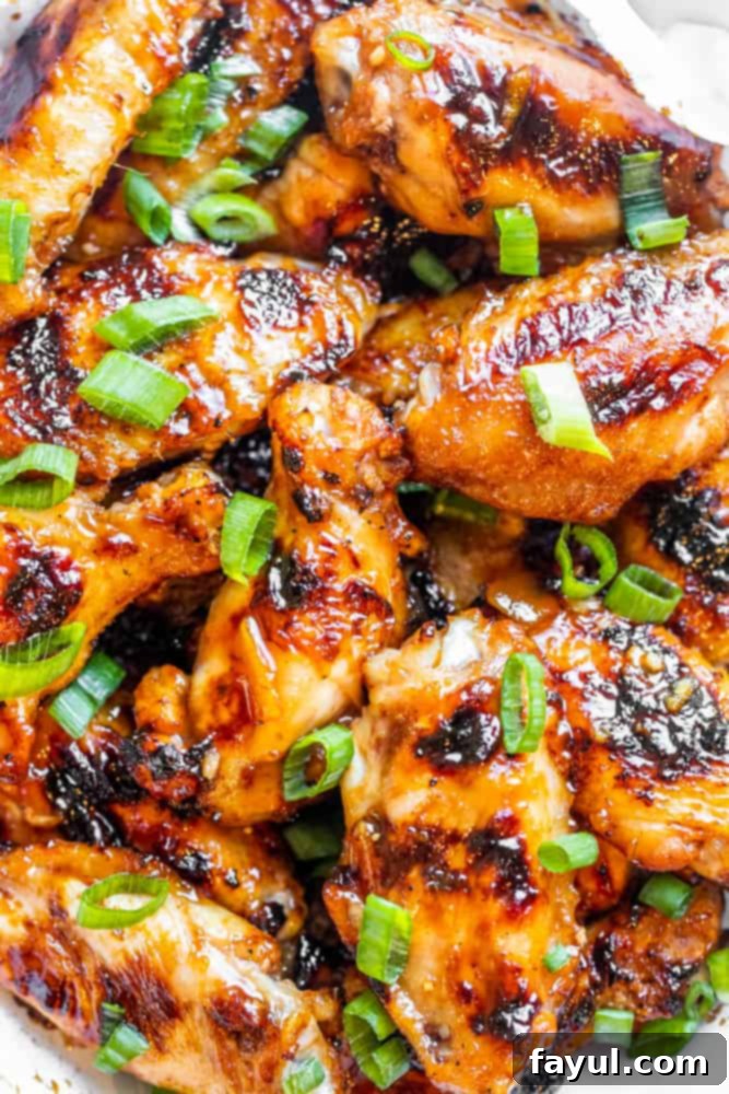 Overhead shot of marinated raw chicken wings in a white bowl, ready for grilling, highlighting the rich peach BBQ sauce coating.