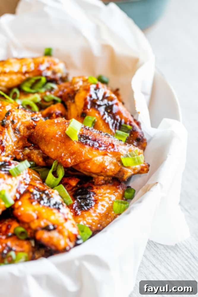 Grilled chicken wings arranged neatly in a white bowl on a white table, ready to be served, with perfect char and glistening sauce.