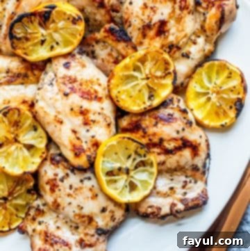 Overhead shot of chicken thighs on a white serving dish on a white counter.