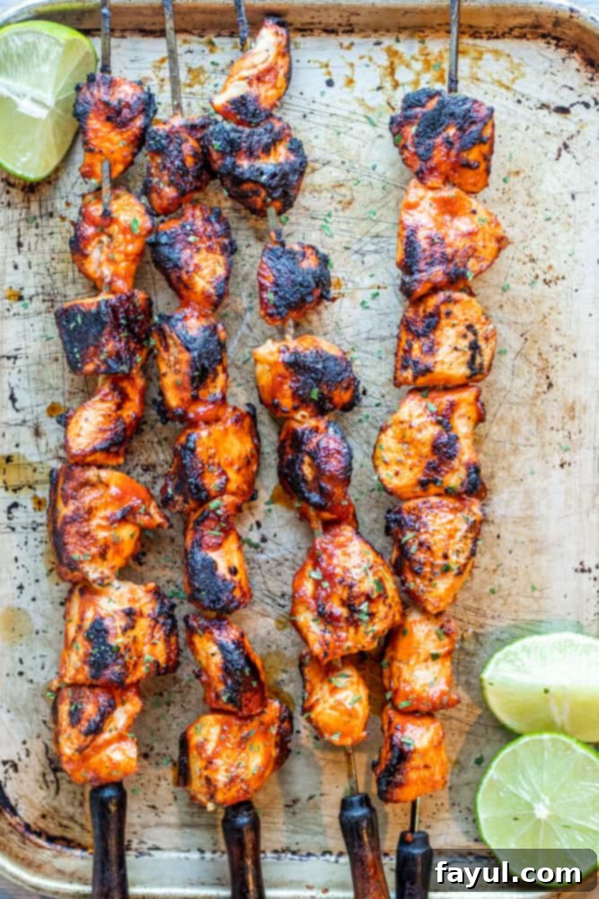 Chipotle Honey Glazed Chicken Skewers 6 Overhead shot of chicken skewers on a metal sheet with sliced limes, ready to serve.