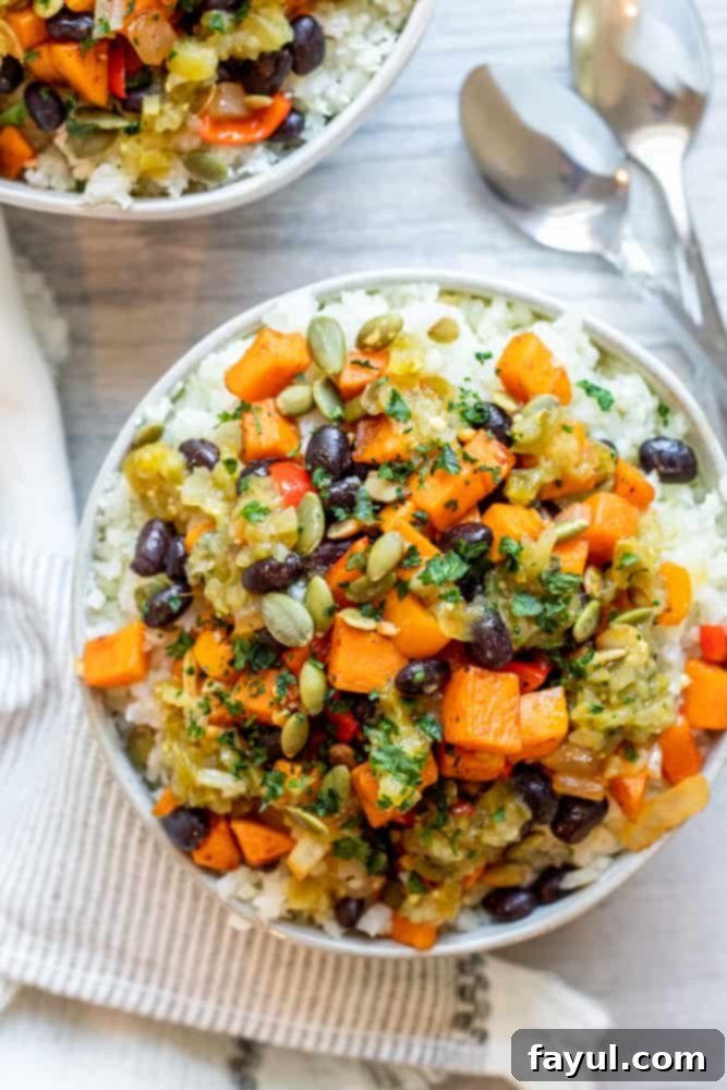 Effortless Veggie Burrito Bowls in Minutes 2 Overhead shot of two bowls of vegan burrito bowl on a white counter with two silver spoons.