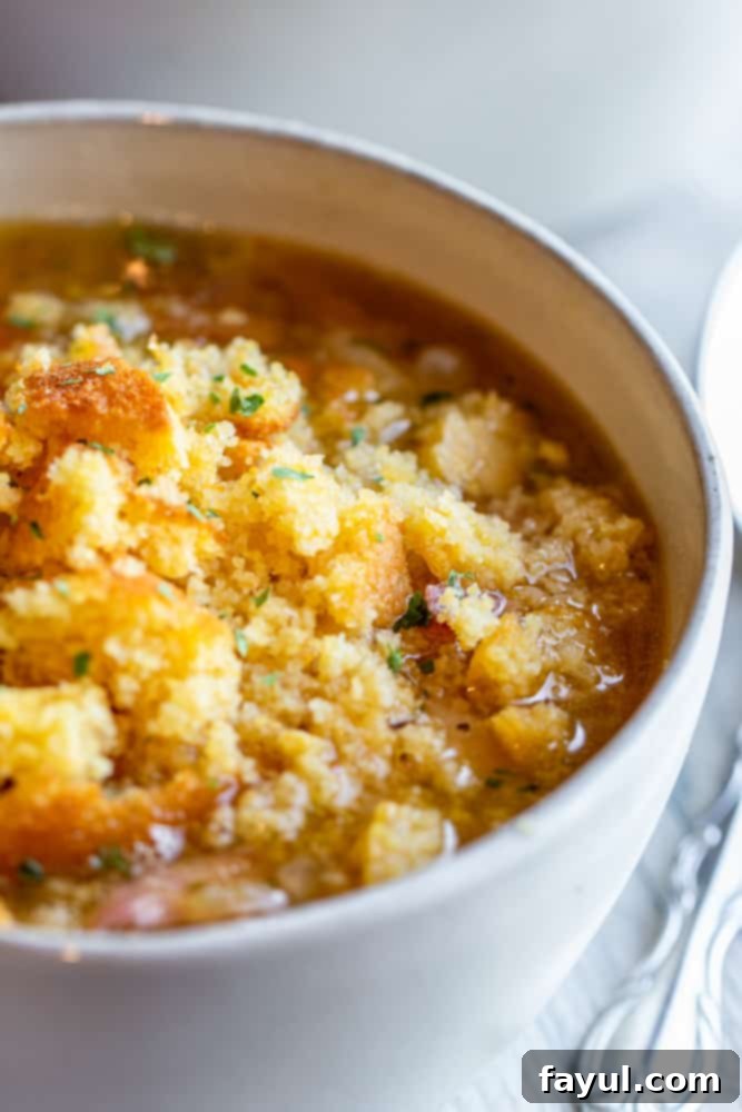 Slow-Cooked Southern Ham and Bean Soup 6 Close up shot of a white bowl filled with ham and bean soup, with a silver spoon resting on the side.