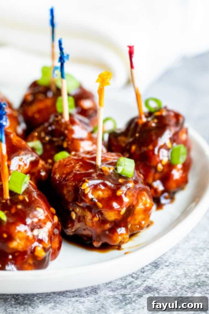 Fiery Asian Pork Meatballs 34 Meatballs on a white plate with toothpicks in them.