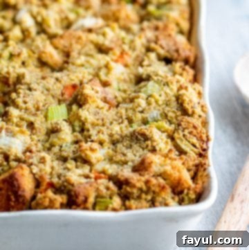 Grandma's Classic Southern Cornbread Dressing 9 Cornbread dressing in a white baking dish with wooden spoon on the side.
