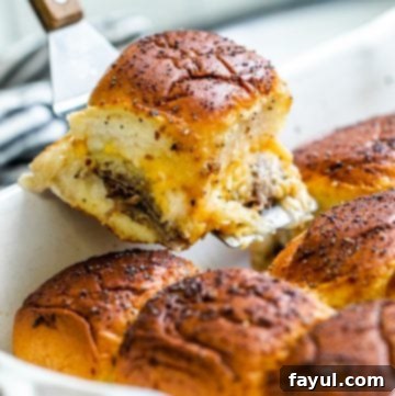 Effortless Baked Roast Beef Sliders 9 Spatula picking up one slider out of white pan.