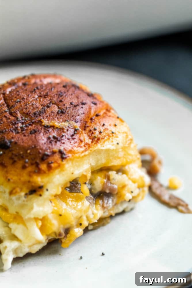 Effortless Baked Roast Beef Sliders 6 Angle shot of roast beef slider on white plate.