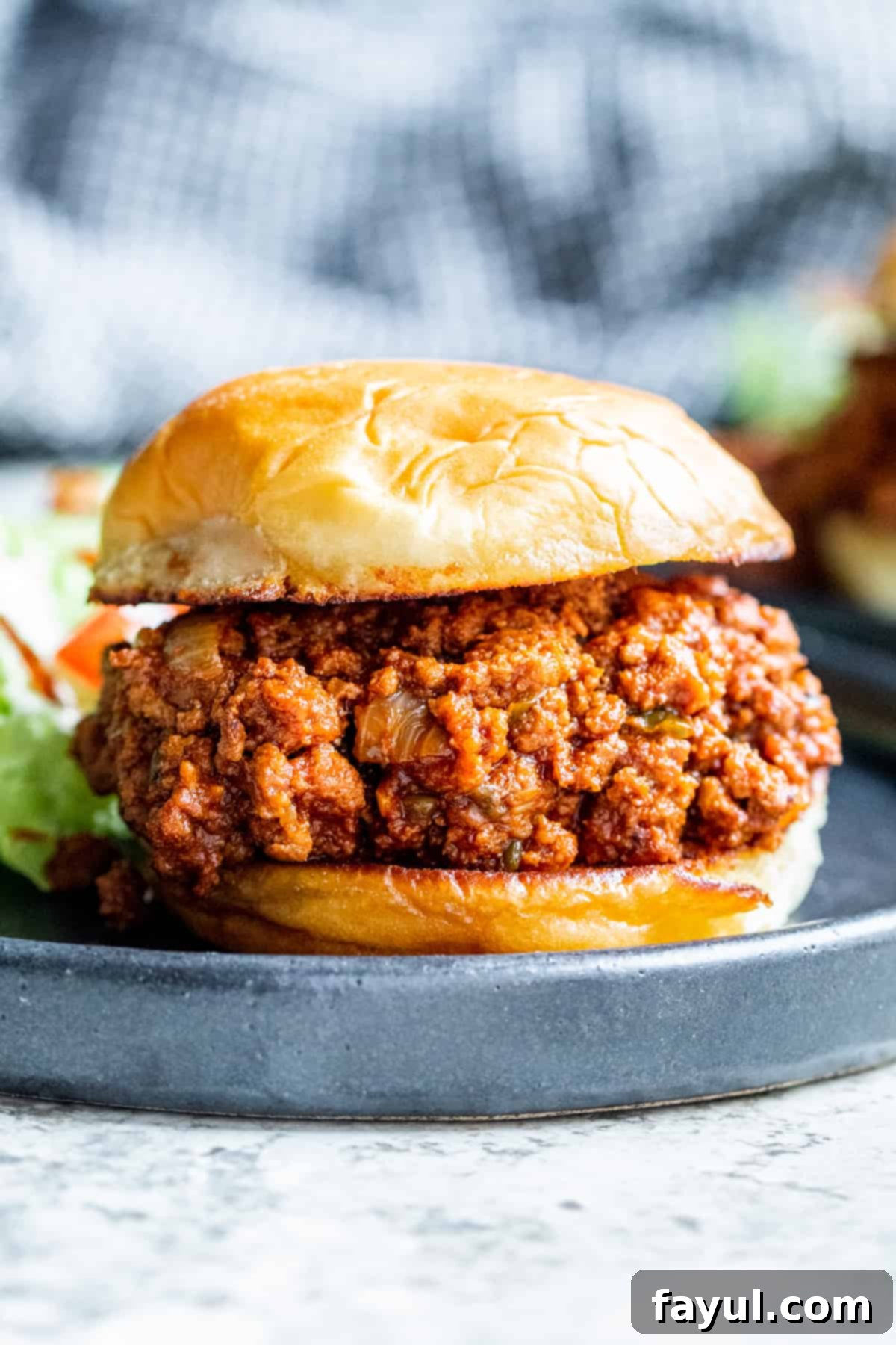 Speedy Instant Pot Ground Turkey Sloppy Joes 22 Strait on shot of sloppy joe sandwich on black plate on white counter.