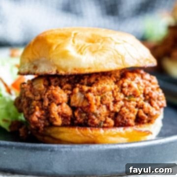 Strait on shot of sloppy joe sandwich on black plate on white counter.