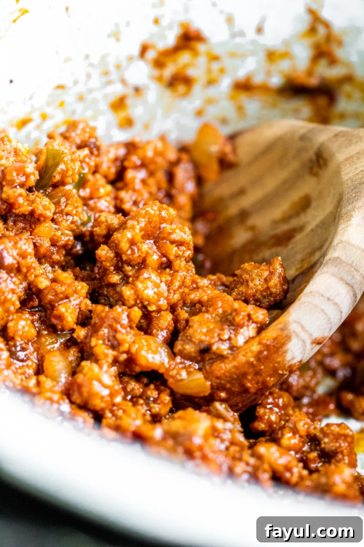 Close up of turkey meat in pot with wooden spoon scooping.