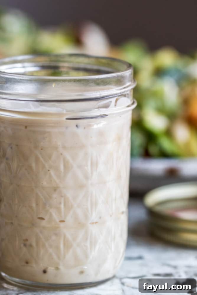 Caesar dressing in mason jar with salad in the background.