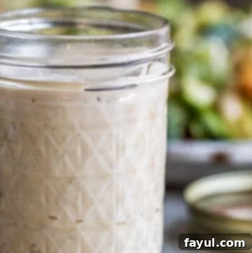 Caesar dressing in mason jar with salad in the background.